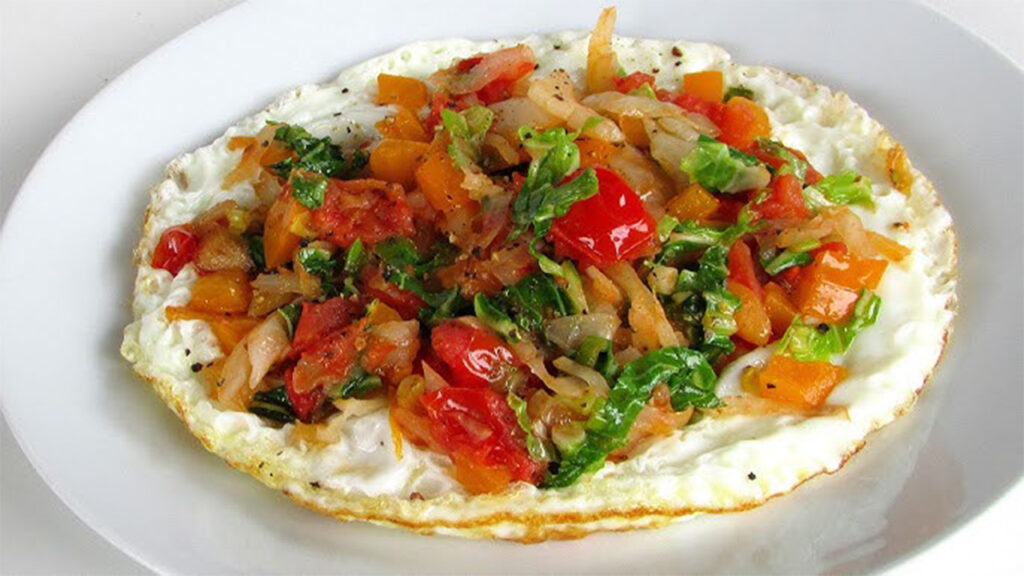 High Protein Low Fat Meals: Colorful omelette with scrambled eggs, bell peppers, spinach, onions, and black pepper.