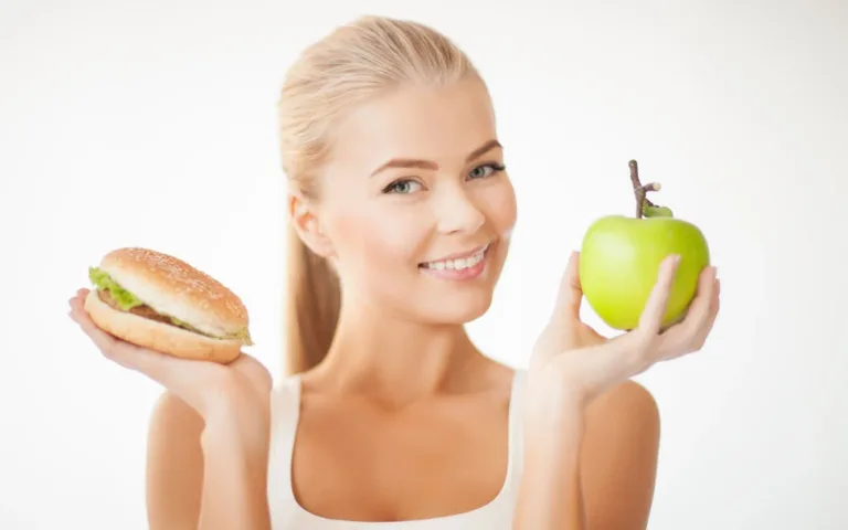 A woman displaying an apple and a hamburger in her hands.