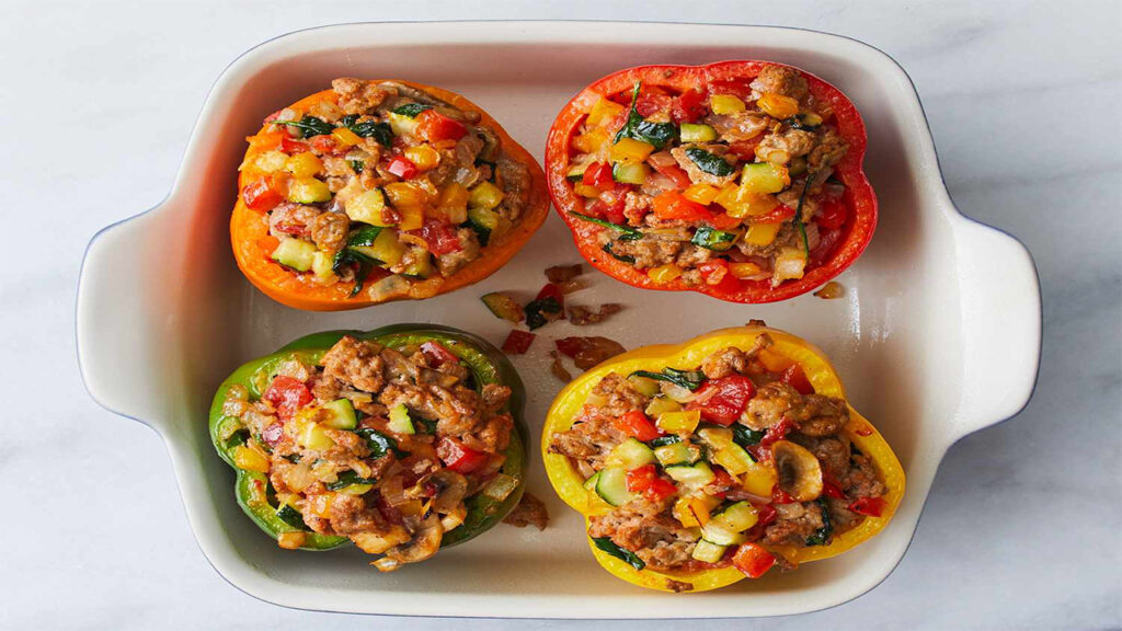Baked stuffed bell peppers (orange, red, green, yellow) filled with ground meat, zucchini, carrots, and red peppers.