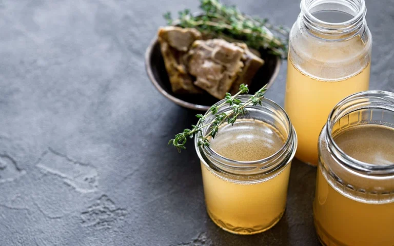 Three jars filled with colorful liquids containing various herbs and spices