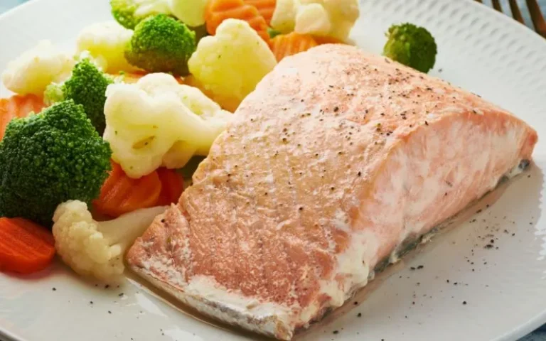 Salmon fillet with colorful vegetables arranged on a plate.