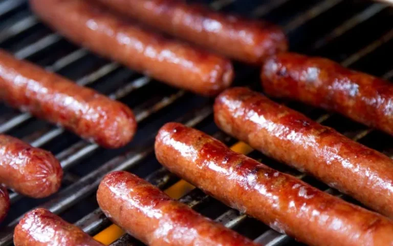 A close-up view of a grill featuring several sizzling hot dogs.