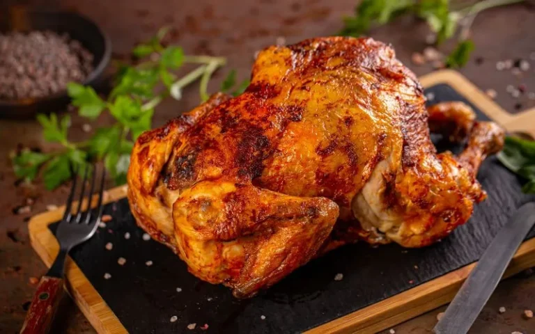 A golden-brown roasted chicken is displayed on a cutting board.