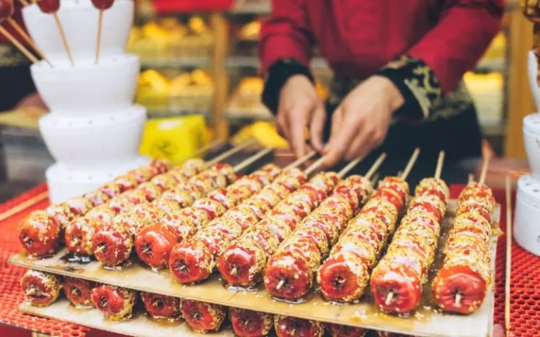 A woman is engaged in the process of preparing skewered food.