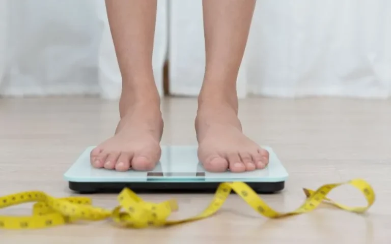 A woman measuring her weight with a yellow tape measur,