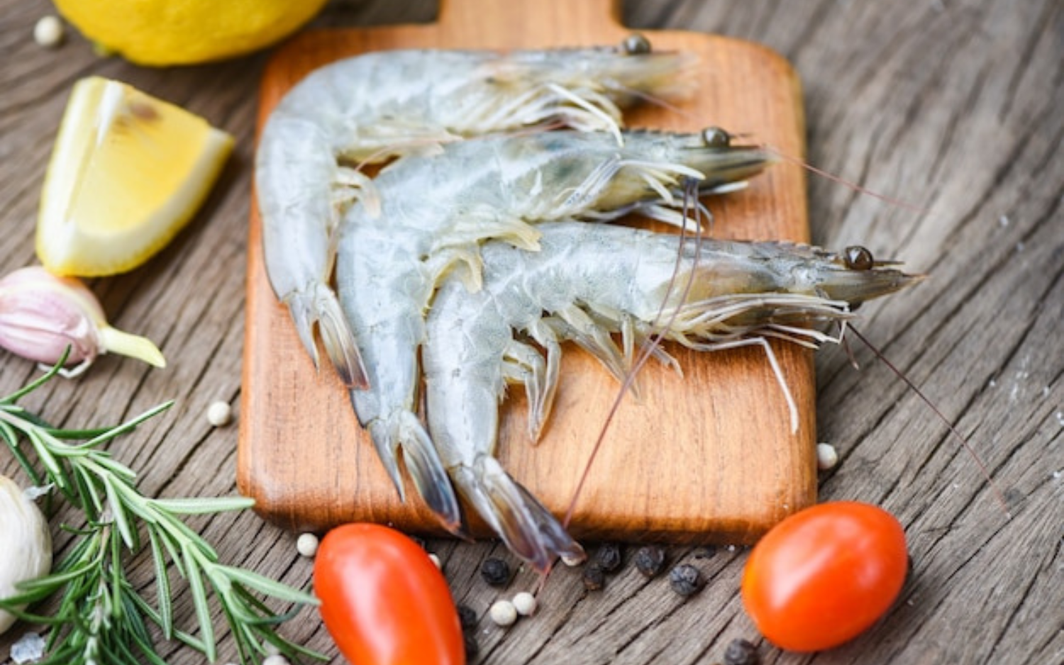 Fresh raw Krill Meat placed on a wooden cutting board, alongside lemon slices and garlic, prepared for cooking