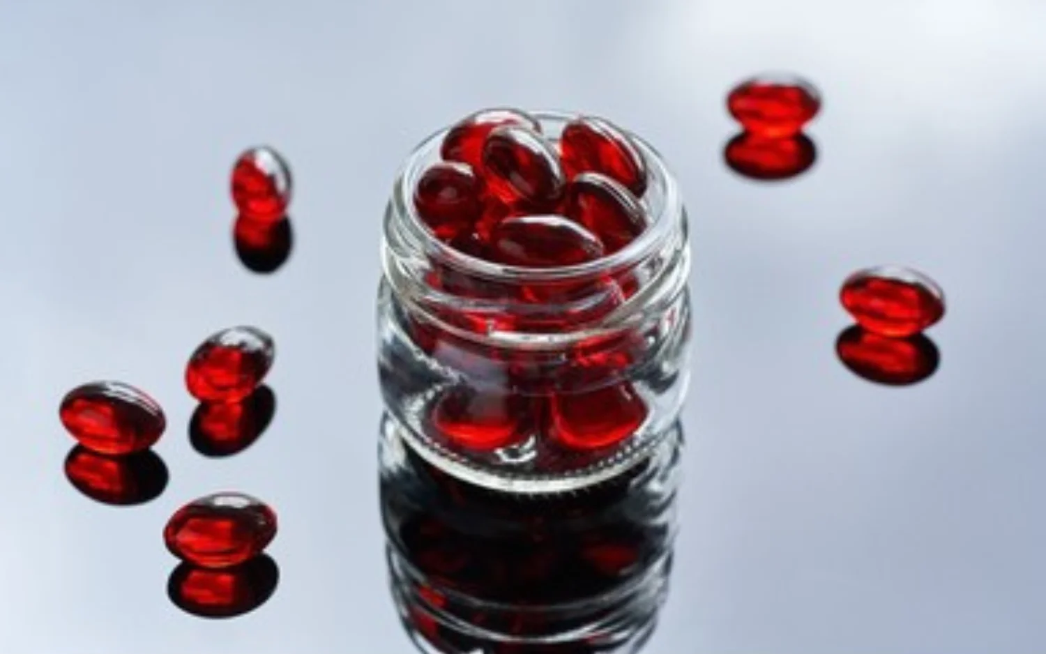 Glass jar containing red fish oil capsules, featuring krill oil inside