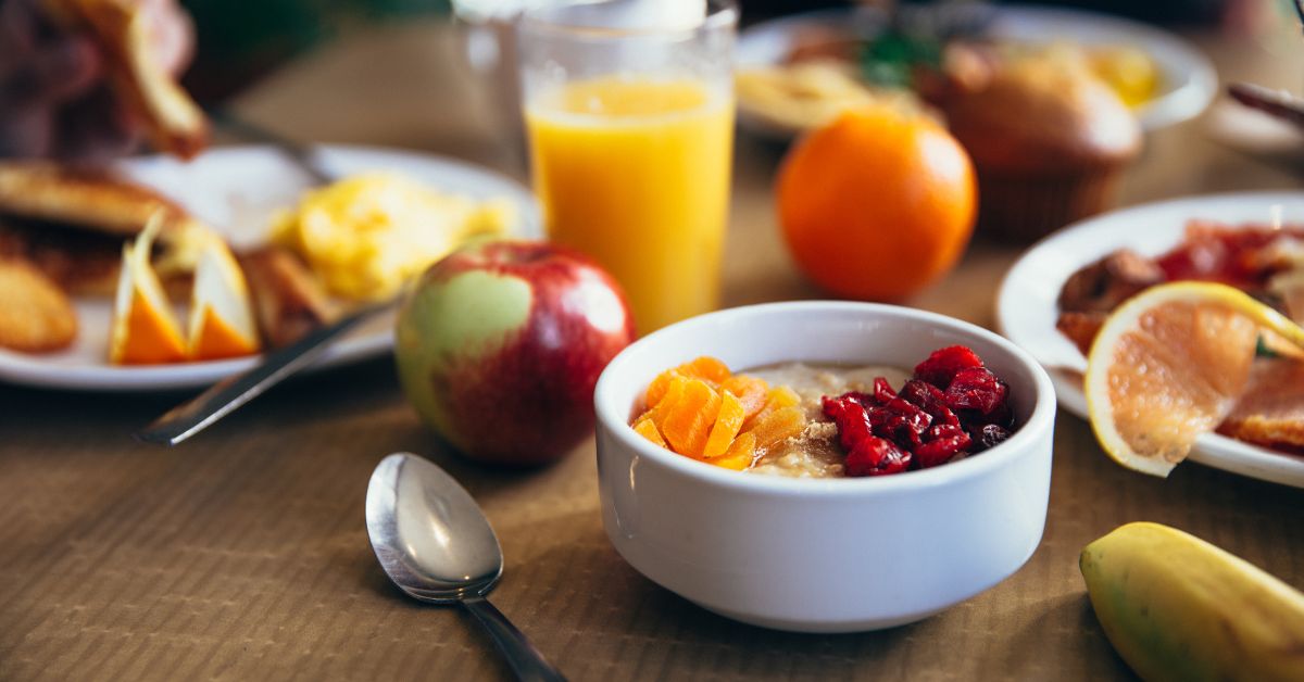 A healthy breakfast spread with oatmeal topped with dried fruits, fresh apple, orange juice, and eggs, ideal for diabetics focused on balanced nutrition