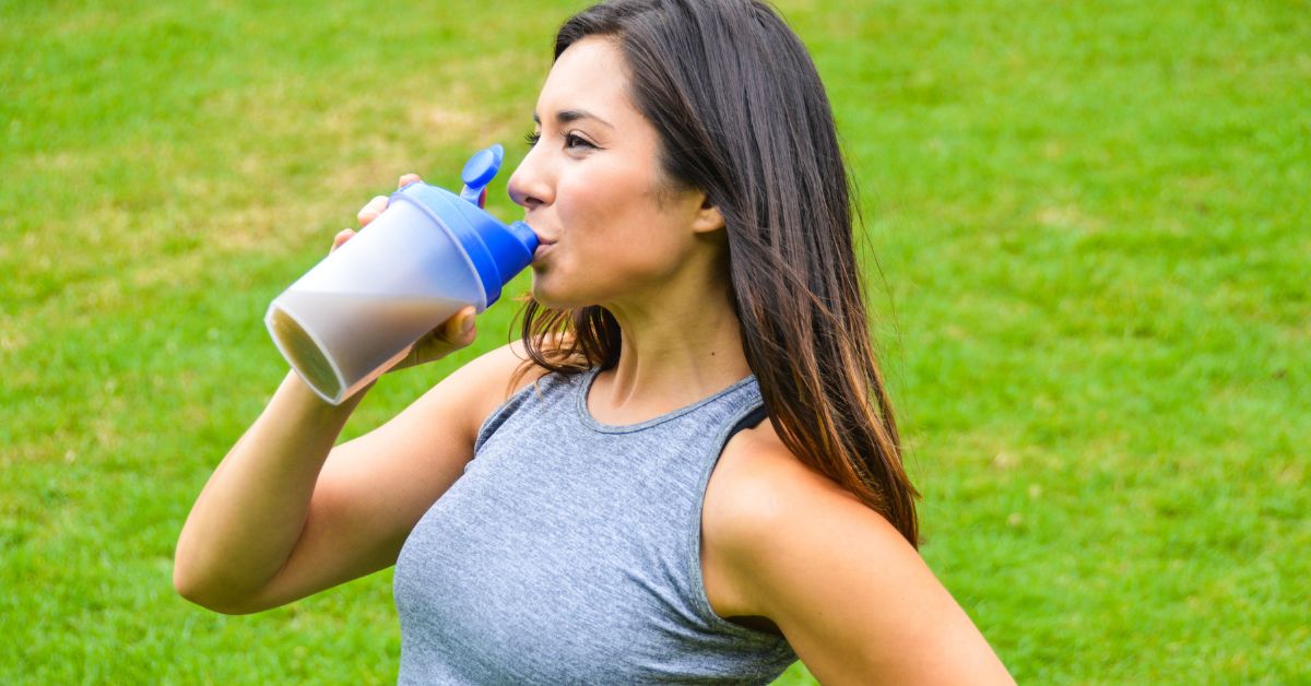 Young woman drinking a nutritious meal replacement shake outdoors.