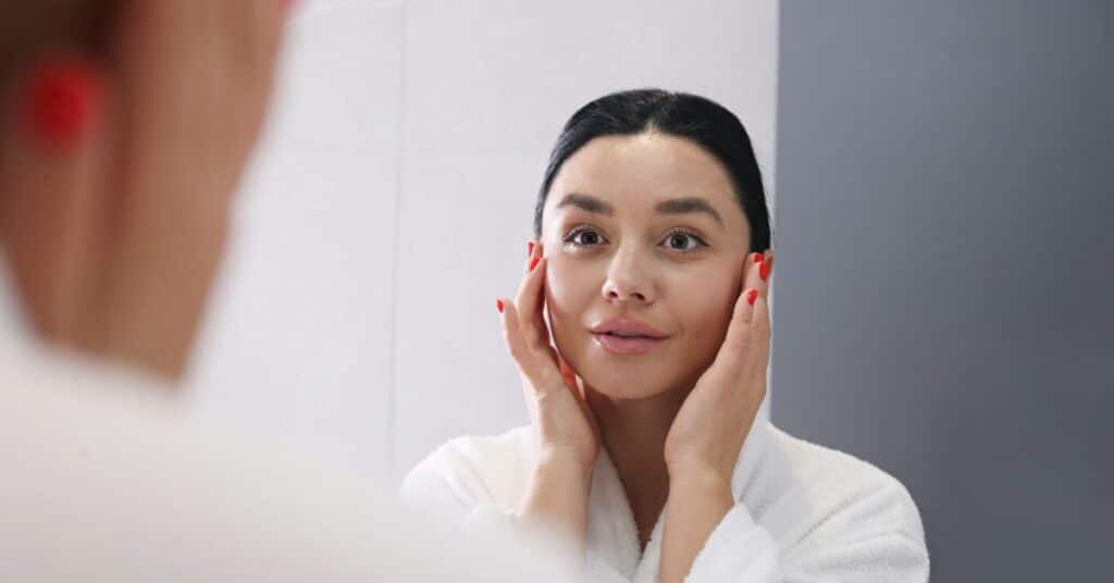 checking her skin health in front of the mirror