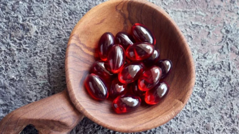 Krill oil capsules displayed in a wooden spoon.