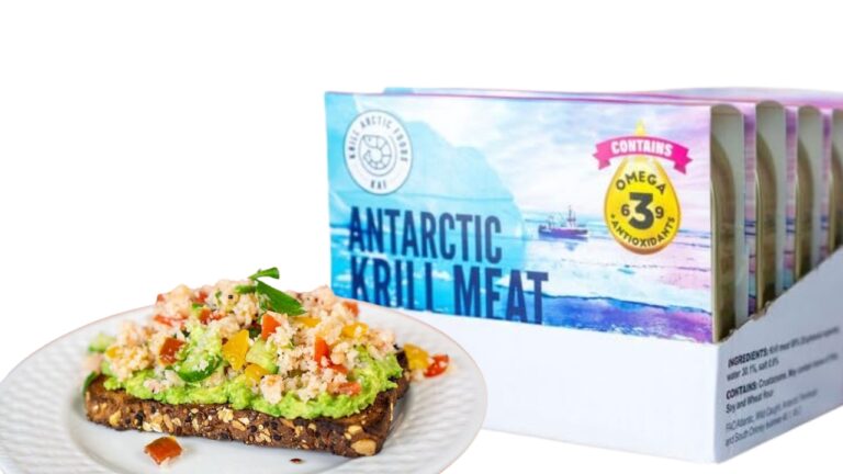 Antarctic Krill Meat on whole grain toast with avocado spread, tomatoes, and peppers. Box labeled "Antarctic Krill Meat" emphasizes Omega-3 & antioxidants. White plate with crumbs.