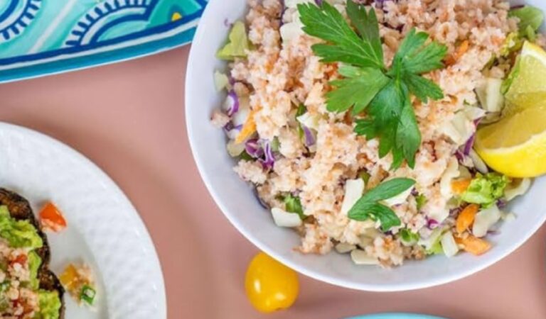 Can Krill Meat Lower Cholesterol? Quinoa salad w/ carrots, cabbage, parsley, lemon wedge, avocado toast, blue cloth on pink table.